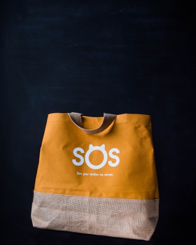 Mala de tecido amarelo e bege com texto SOS e frase em branco