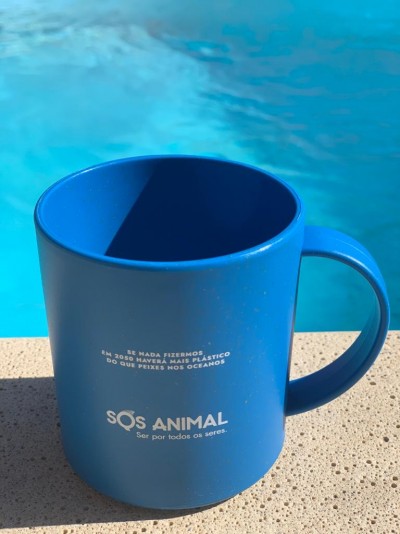 Caneca azul com texto branco junto à piscina