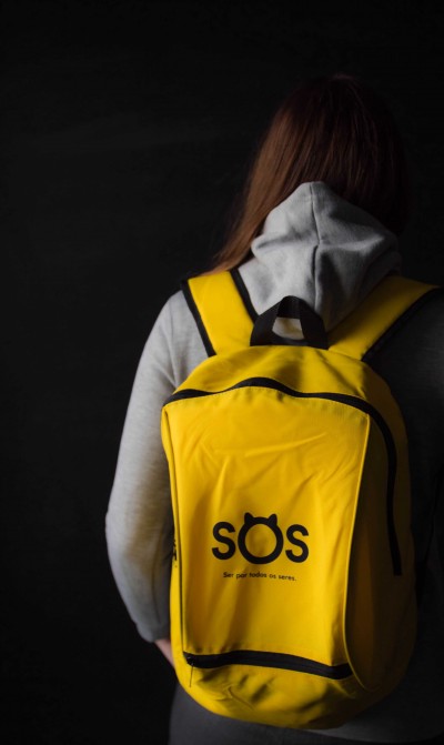 Mochila amarela com texto 'sós' e frase inspiradora