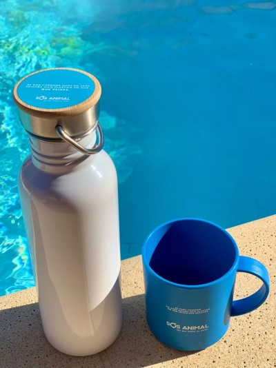 Garrafa branca com tampa de madeira e caneca azul perto de piscina