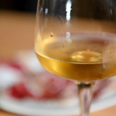 Taça com vinho branco e prato ao fundo desfocado