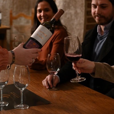 Garrafa de vinho e taças com pessoas em ambiente interno acolhedor