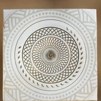 Frasco de perfume Nusuk com embalagem branca e dourada, grãos dourados e perfume Falak em destaque