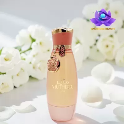 Frasco de perfume rosa e dourado com texto MUTHEER Elixir e flores brancas ao fundo