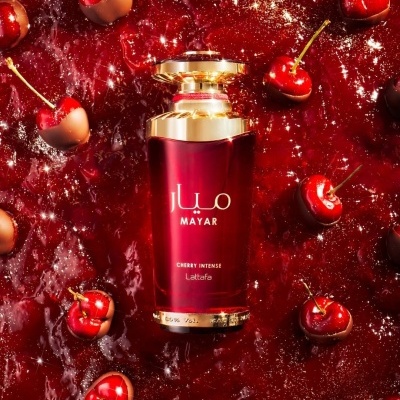 Frasco de perfume Mayar Cherry Intense com cerejas e chocolate sobre superfície vermelha