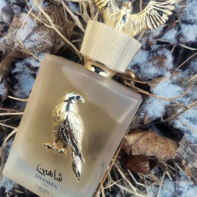 Frasco de perfume com falcão dourado sobre folhas secas