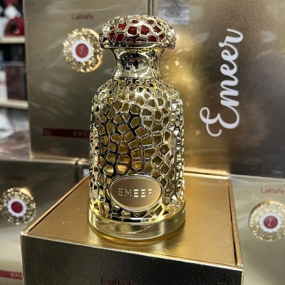 Frasco de perfume dourado e vermelho EMEEER sobre caixa dourada
