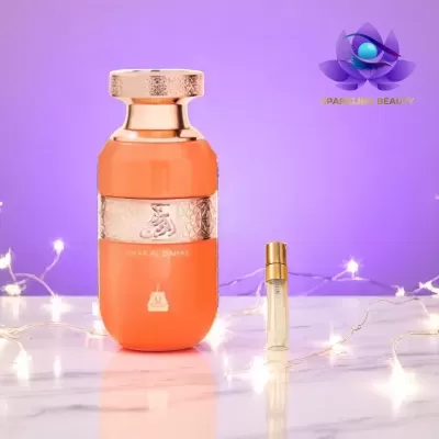 Frasco laranja e dourado de perfume e pequeno frasco junto em fundo roxo com luzes brancas