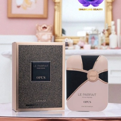 Frasco e caixa de perfume Le Parfait OPUS ARMAF sobre mesa branca em ambiente decorado em tons rosa e dourado