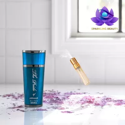 Frasco azul de perfume ARMAF em bancada branca com pétalas e spray, logo Sparkling Beauty