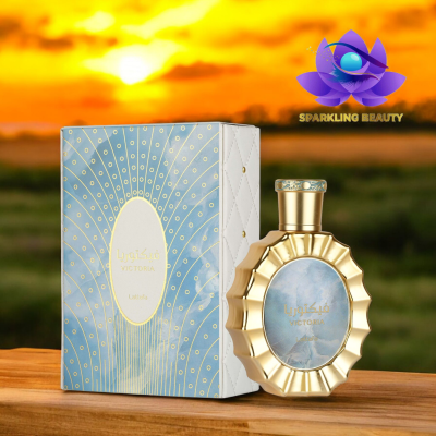 Frasco dourado de perfume Victoria Latifa e caixa azul decorada sobre madeira com fundo de pôr do sol