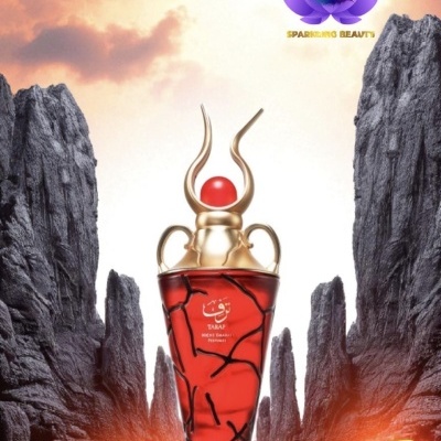 Frasco de perfume vermelho e dourado entre rochas com céu alaranjado