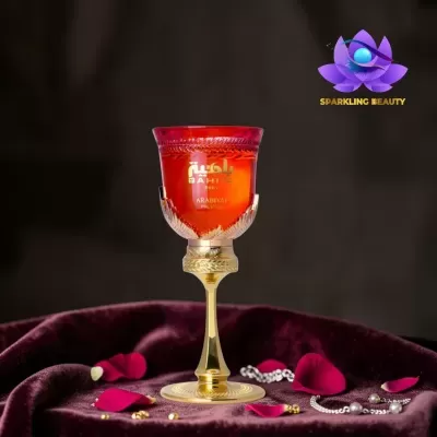 Copo vermelho decorativo com base dourada sobre tecido roxo e pétalas