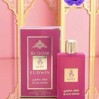 Frasco e caixa de perfume rosa com detalhes dourados e texto AYAT BLOOM EUDWIN