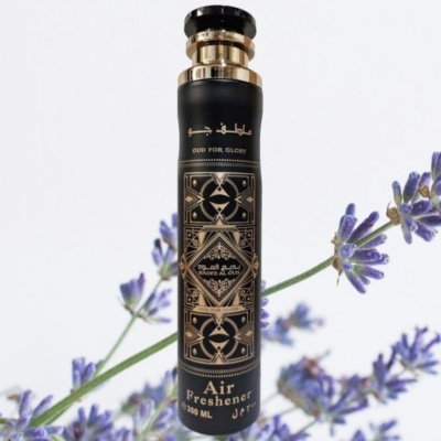 Frasco preto e dourado de ambientador com flores roxas ao fundo