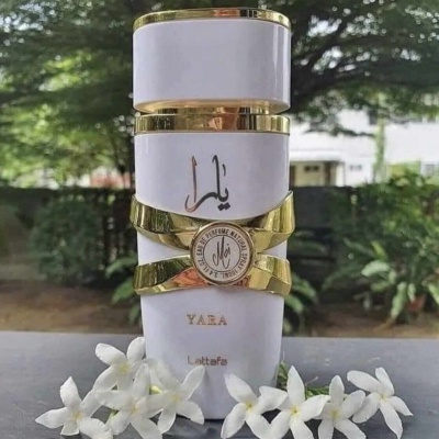 Frasco de perfume Yaza branco e dourado com flores brancas ao redor