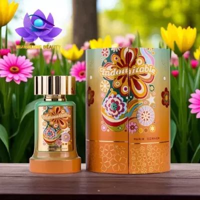 Frasco e caixa de perfume Indomitable com design floral colorido em ambiente com flores amarelas e rosas.