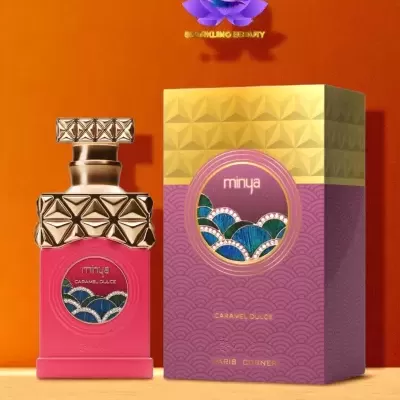 Frasco de perfume cor-de-rosa com tampa dourada decorada, ao lado de caixa creme e rosa com padrão geométrico