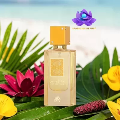 Frasco de perfume transparente com tampa amarela sobre folhas verdes e flores coloridas