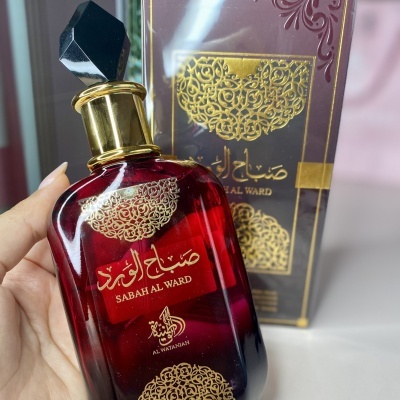 Frasco de perfume vermelho com tampa preta e detalhes dourados, com caixa preta e dourada ao fundo.
