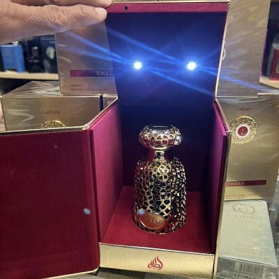 Frasco de perfume dourado em caixa iluminada vermelha e dourada