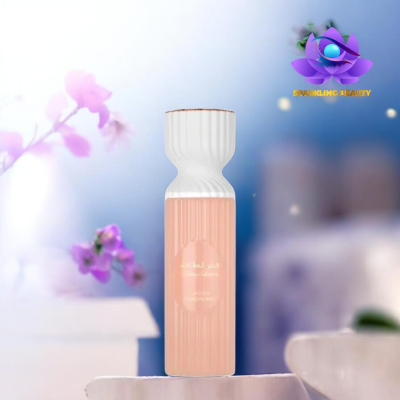 Frasco de perfume rosa claro com tampa branca ondulada sobre superfície branca com flores lilases ao fundo