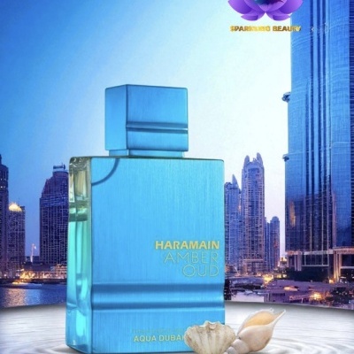 Frasco de perfume azul com texto dourado e conchas, com fundo de arranha-céus ao entardecer