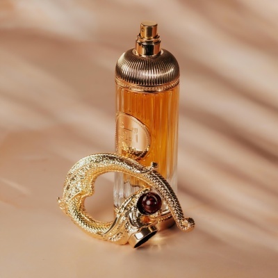 Frasco de perfume dourado com adorno dourado e pedra vermelha