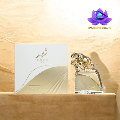 Frasco de perfume com tampa de pantera dourada ao lado de caixa branca e dourada sobre superfície bege