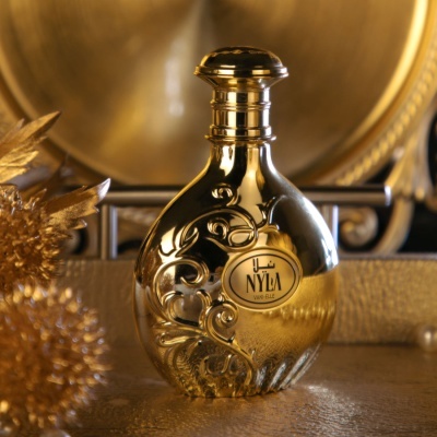 Frasco de perfume dourado com decoração em relevo e rótulo 'NYLA Eau de Parfum'
