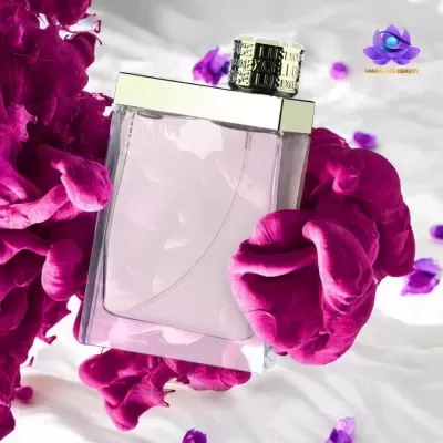 Frasco de perfume com líquido rosa rodeado por pétalas coloridas