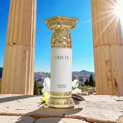 Frasco de perfume branco e dourado entre colunas antigas ao sol