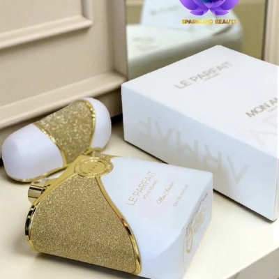 Frasco de perfume branco e dourado com caixa branca ao lado numa superfície clara.