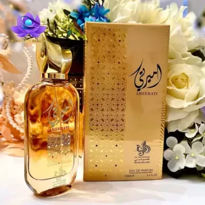 Frasco e caixa dourada de perfume Ameerati com flores brancas ao fundo
