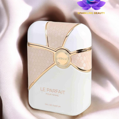 Frasco de perfume branco e bege com detalhes dourados sobre tecido de cetim rosa claro