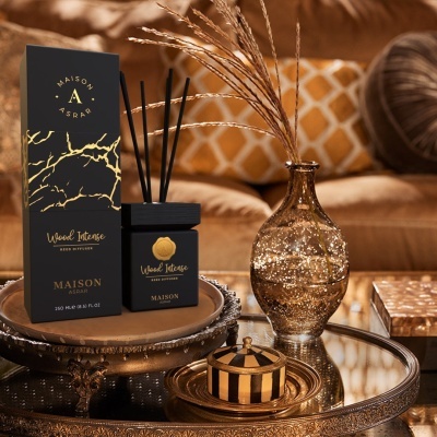 Difusor de aroma preto e dourado com vaso decorativo e caixa numa mesa redonda num ambiente aconchegante.