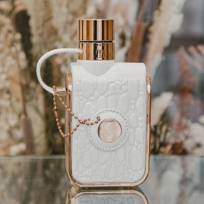 Frasco de perfume branco texturizado com detalhes dourados e corrente dourada