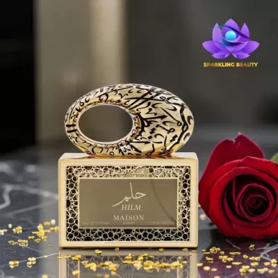 Frasco de perfume dourado decorativo com tampa oval e rosa vermelha ao lado