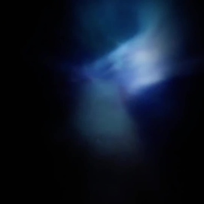 Frasco preto de perfume Musamam Black Intense em fundo escuro com luz azul e folhas verdes