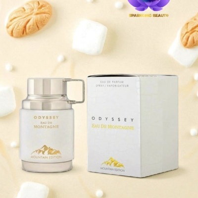Frasco e caixa de perfume Odyssey Eau de Montagne Mountain Edition branco e dourado, com fundo creme decorado com marshmallows e bolachas