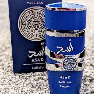 Frasco azul prateado com texto ASAD ZANZIBAR Lattafa e embalagem com design circular