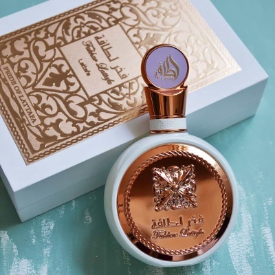 Frasco de perfume branco com detalhes em cobre sobre caixa branca decorativa