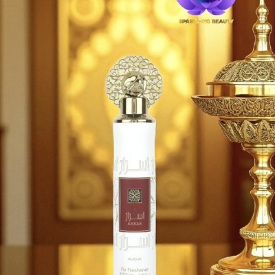 Frasco branco de spray ambientador com tampa prateada e objeto decorativo dourado