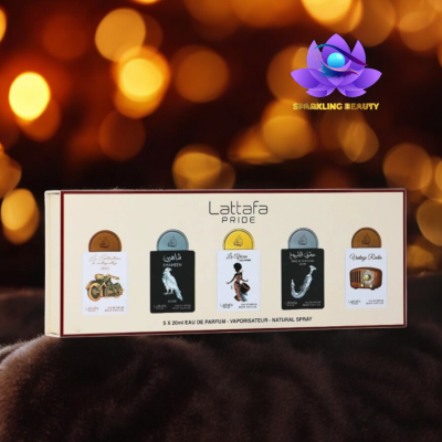 Conjunto de perfumes Lattafa Pride com cinco designs distintos da embalagem sobre superfície de tecido escuro e luzes douradas desfocadas no fundo.