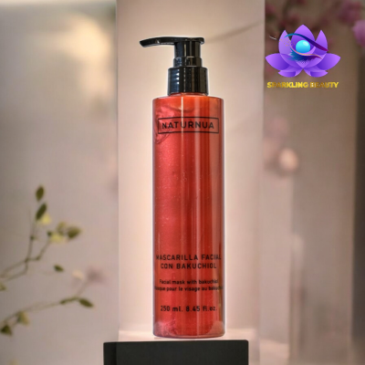 Frasco vermelho translúcido de máscara facial NATURNUA com bomba preta, texto em várias línguas, em base preta e fundo neutro.