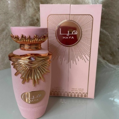 Frasco de perfume rosa e dourado com embalagem rosa com texto HAYA