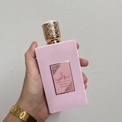Frasco de perfume rosa com tampa dourada e rótulo metálico
