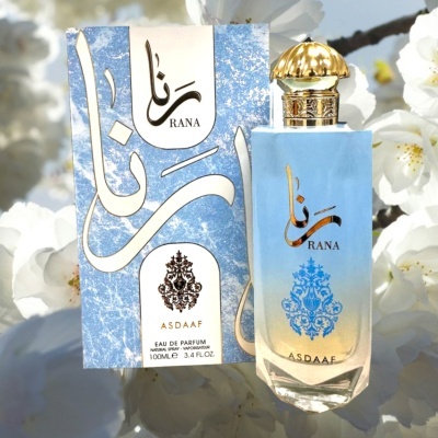 Perfume RANA ASDAAF com embalagem azul e dourada em fundo de flores brancas.