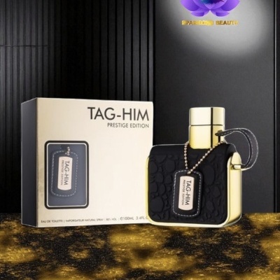 Frasco de perfume TAG-HIM Prestige Edition preto e dourado ao lado da caixa em fundo escuro