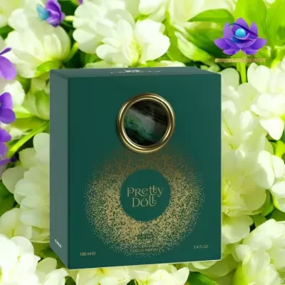 Caixa verde de perfume Pretty Doll com detalhes dourados, rodeada por flores brancas e verdes